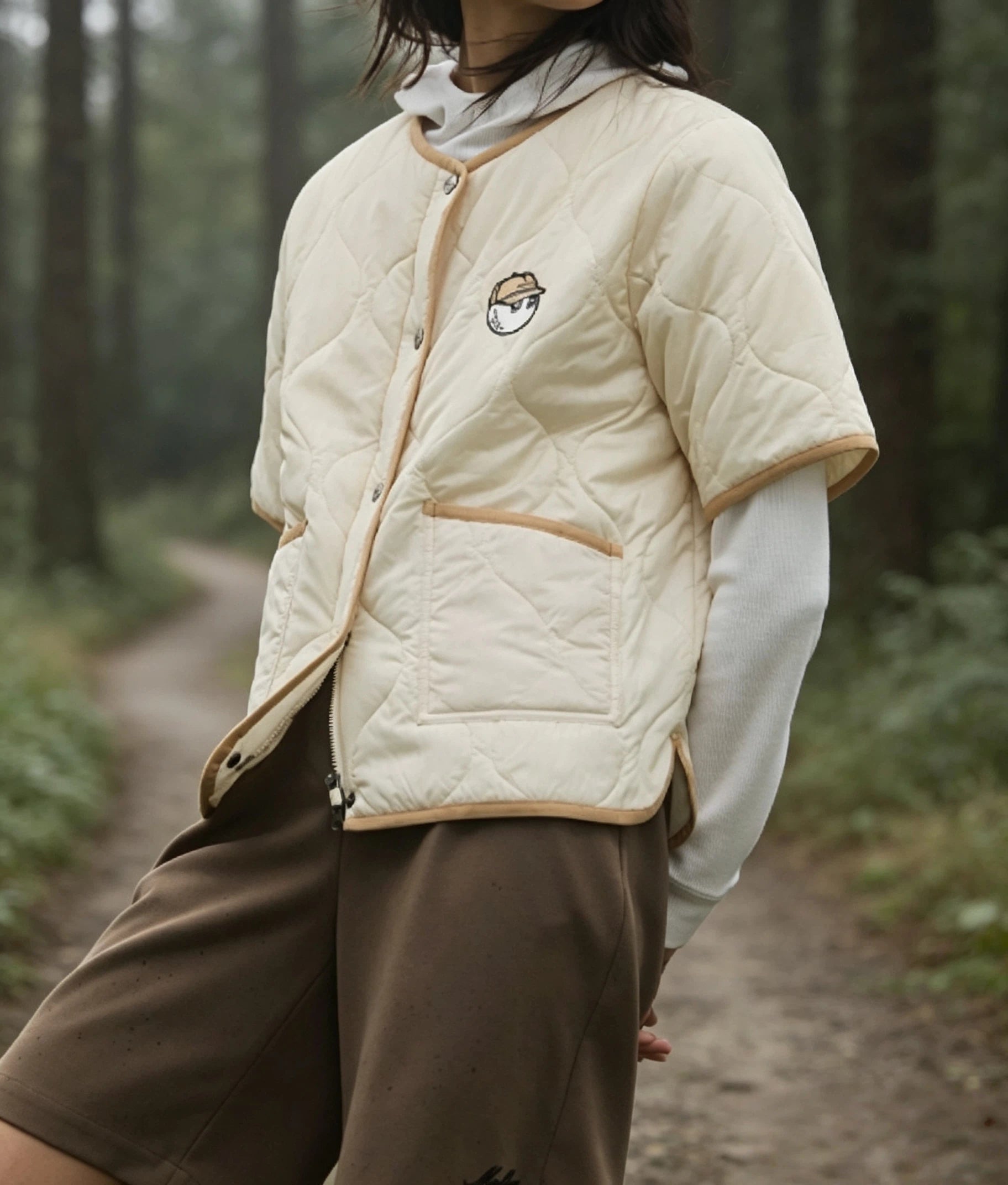 Malbon women's short-sleeve insulated padded golf jacket in Cream, branding detail