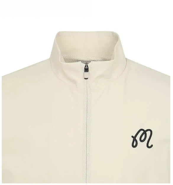 Close-up of beige Malbon golf vest collar and chest logo
